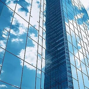 Fensterfront eines Bankgebäudes in der sich der Himmel spiegelt